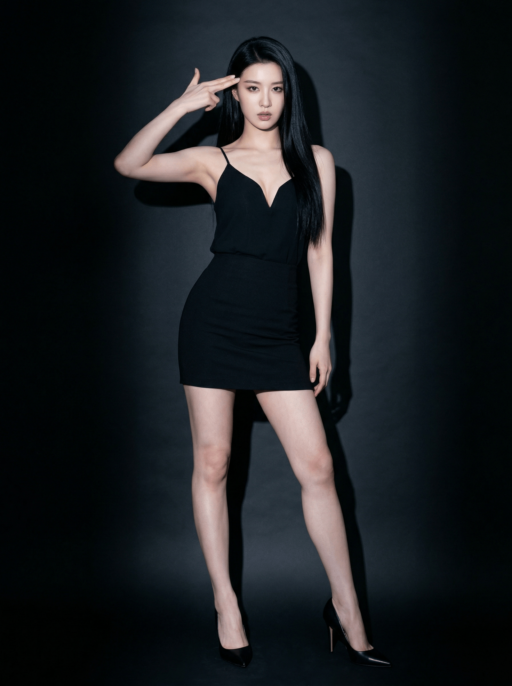 Studio portrait of a woman posing in a fitted black dress and high heels against a dark background