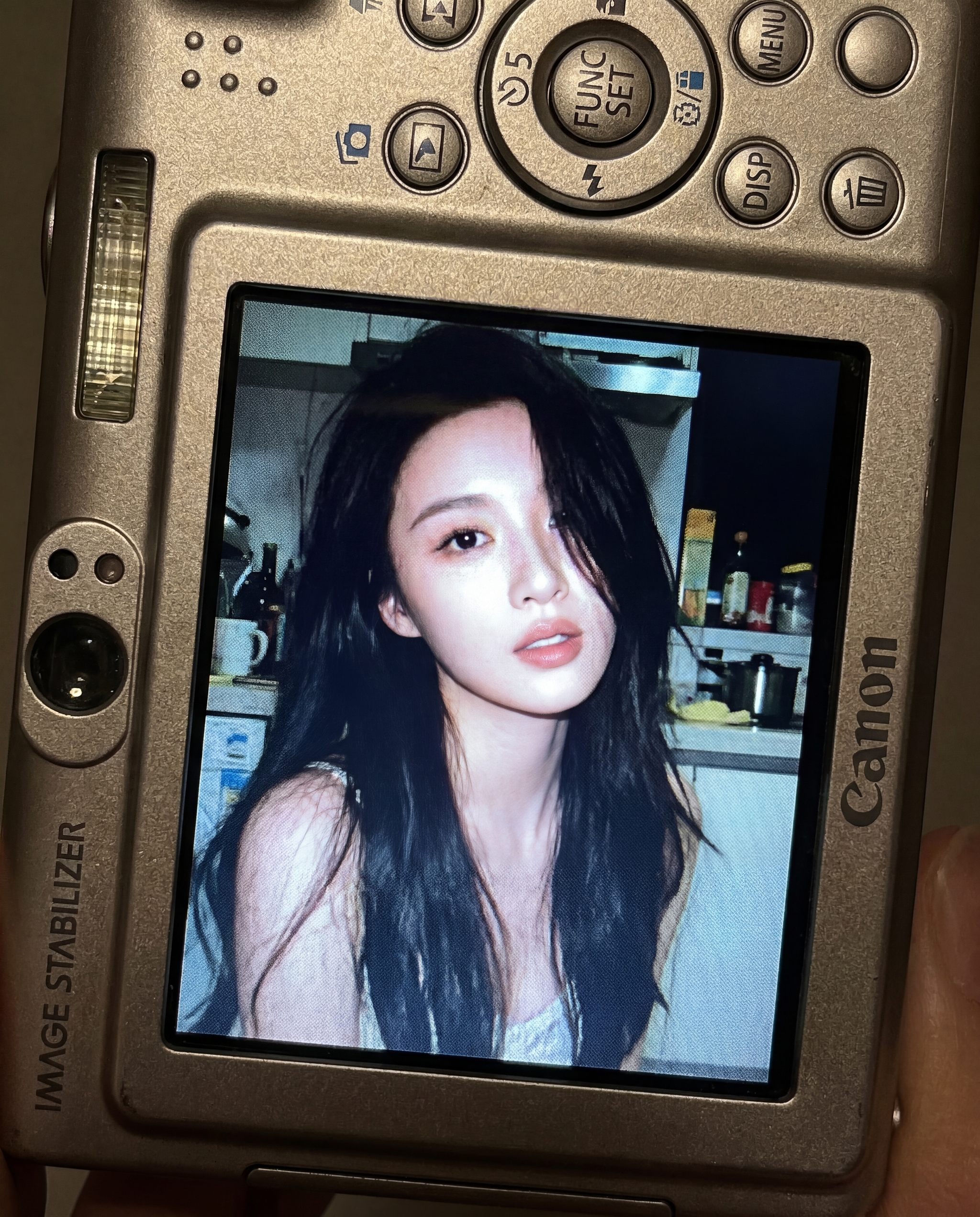 Close up of a Canon digital camera showing a portrait photo on its LCD screen with the face blurred