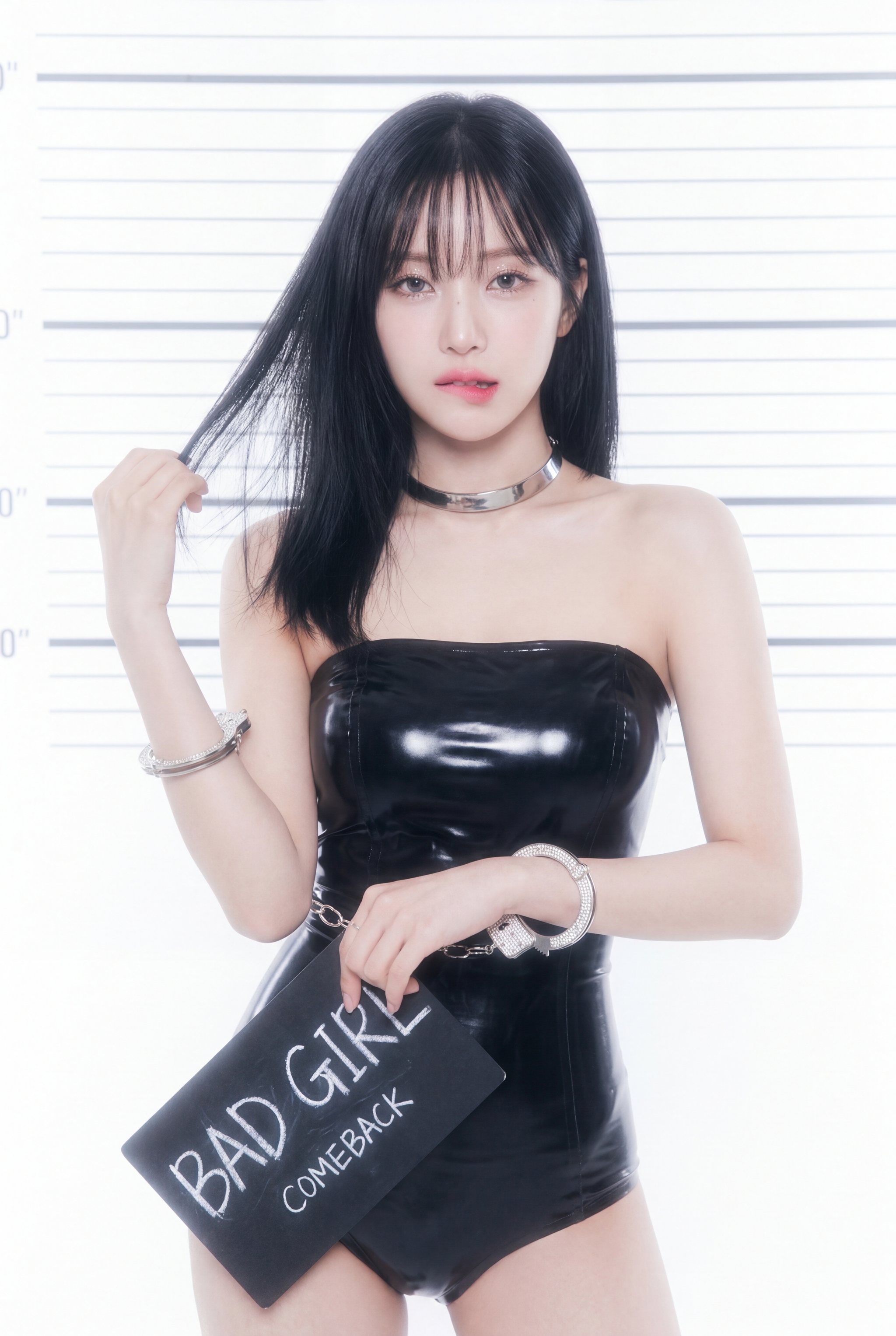 Woman in a black strapless latex bodysuit holding a BAD GIRL clutch against a bright striped backdrop