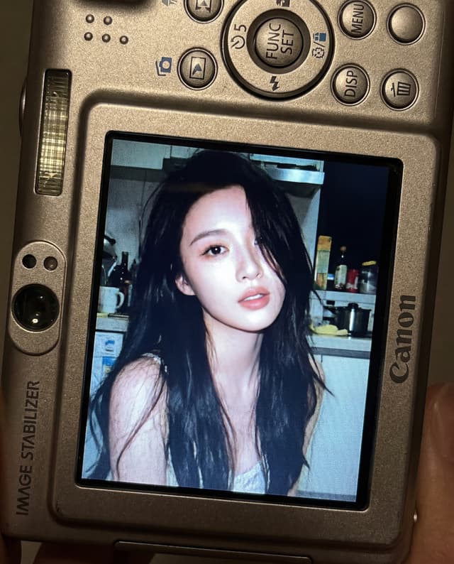 Close up of a Canon digital camera showing a portrait photo on its LCD screen with the face blurred